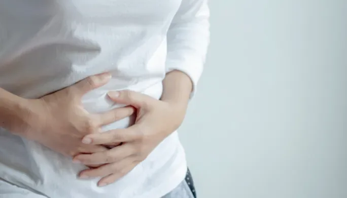 Close-up of hands pressed over the midline abdomen, illustrating diastasis recti