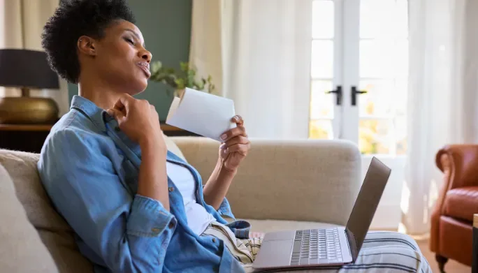 Woman relaxing at home reviewing paperwork, reflecting on new symptoms and changes during perimenopause