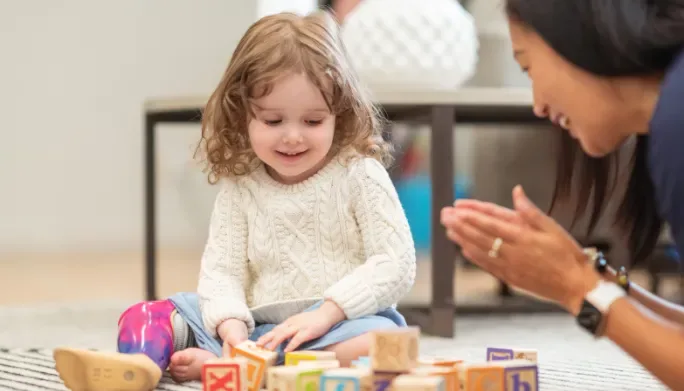 Young child playing with blocks alongside a caregiver during a pediatric pelvic care session
